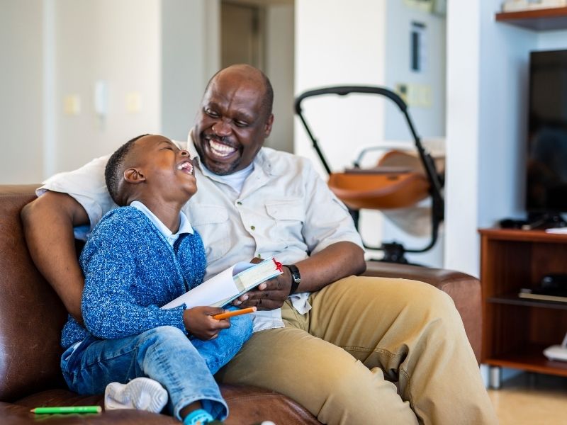 Grandfather and son laughing with a book